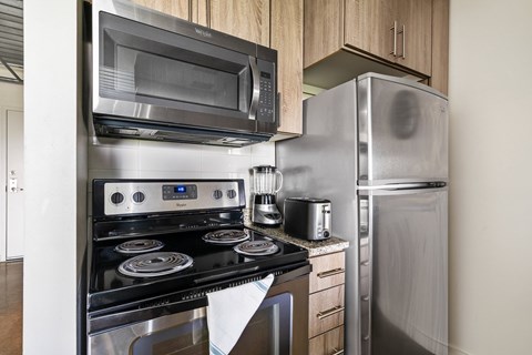 A modern kitchen with a stainless steel refrigerator, microwave, oven, and toaster.