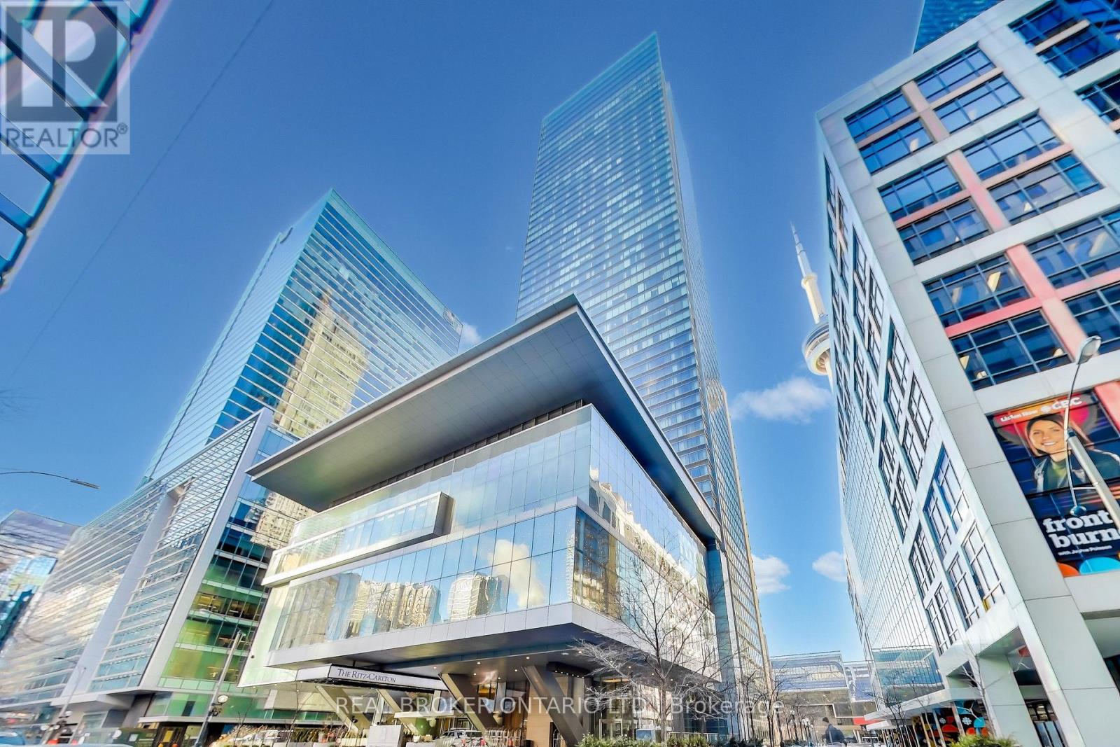 A modern building with a glass facade stands tall among other skyscrapers.