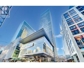 A modern building with a glass facade stands tall among other skyscrapers.