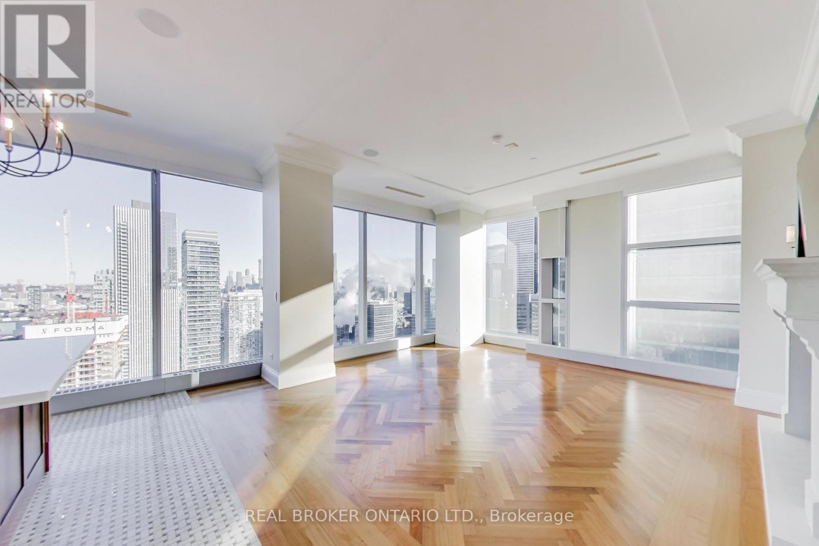 A spacious room with wooden floors and large windows overlooking a cityscape.