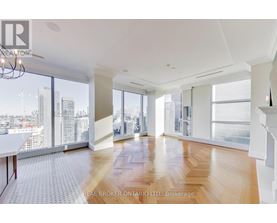 A spacious room with wooden floors and large windows overlooking a cityscape.