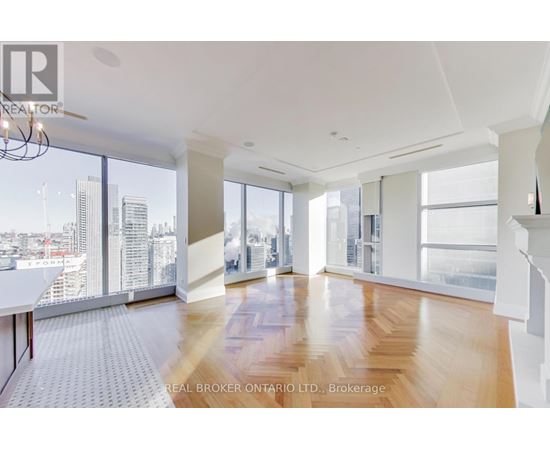 A spacious room with wooden floors and large windows overlooking a cityscape.
