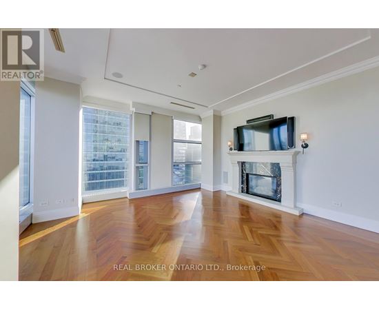 A spacious living room with wood flooring and a fireplace.