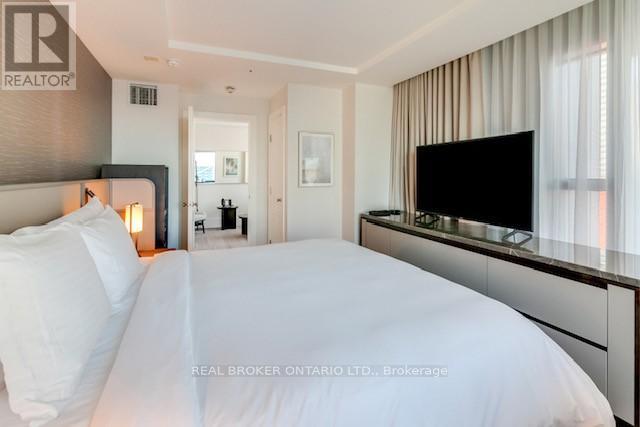 A bedroom with a large bed and a flat screen TV mounted on the wall.