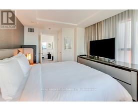 A bedroom with a large bed and a flat screen TV mounted on the wall.