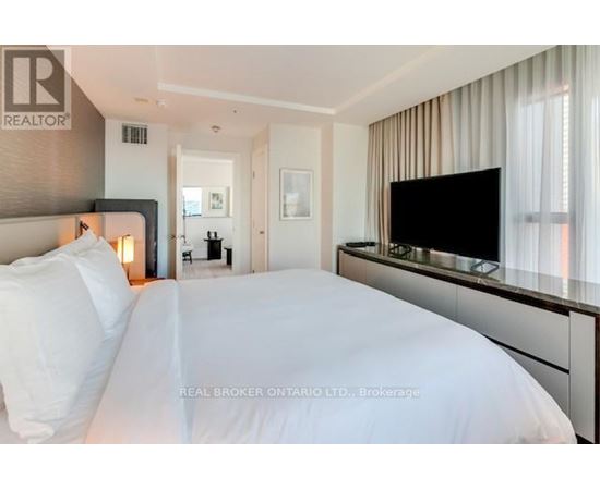 A bedroom with a large bed and a flat screen TV mounted on the wall.