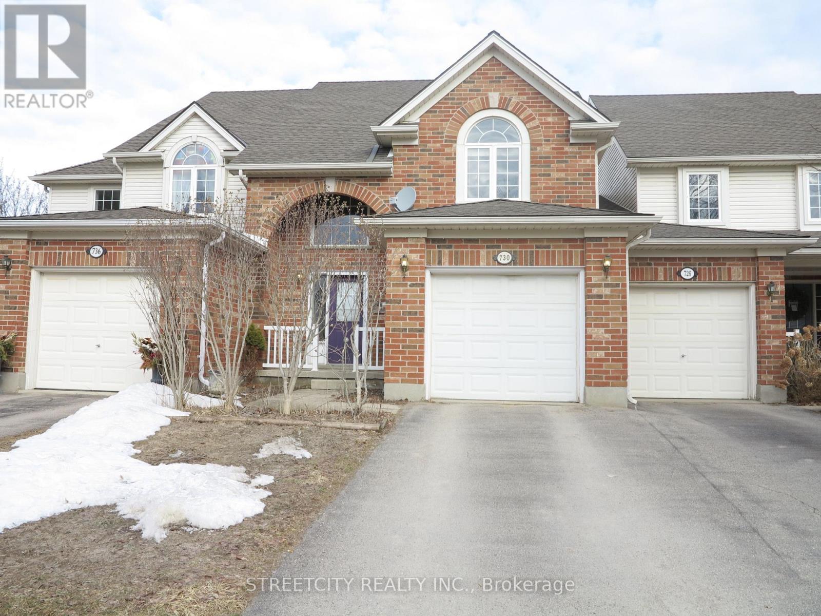 A brick house with a garage door is for sale.