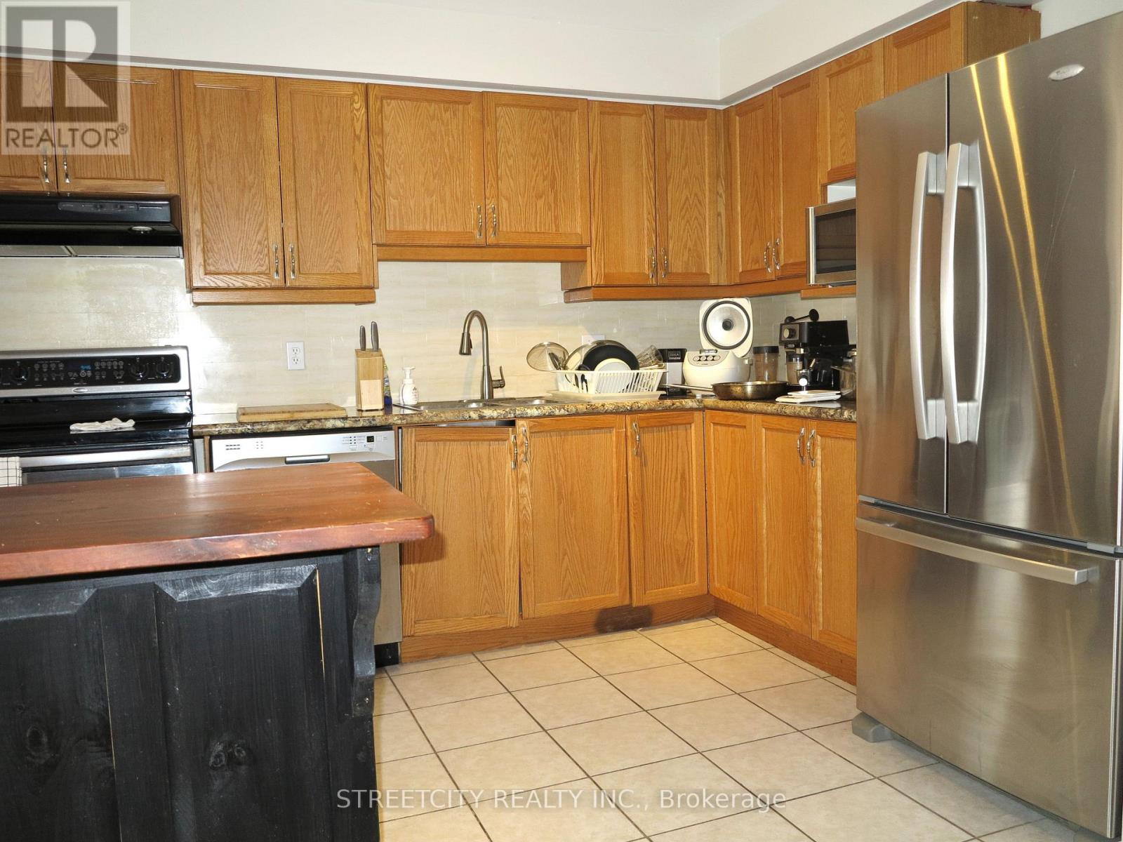 A kitchen with wooden cabinets and a stainless steel refrigerator.