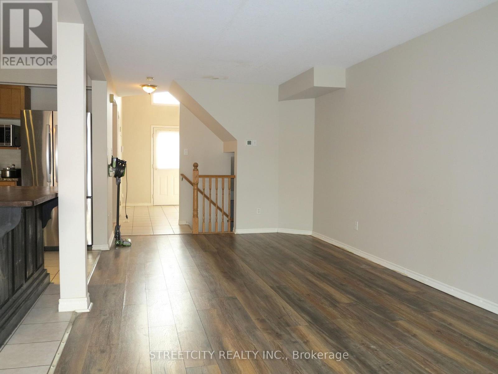 A spacious room with wooden flooring and white walls, part of a residential property.