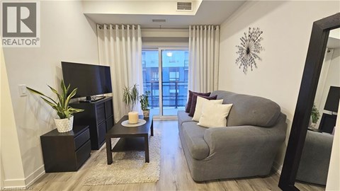 A living room with a grey couch and a black dresser.