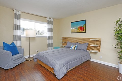 a bedroom with a bed and a chair and a window