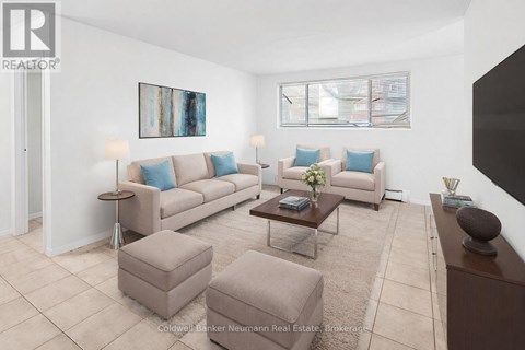 A living room with a couch, ottoman, and a painting on the wall.
