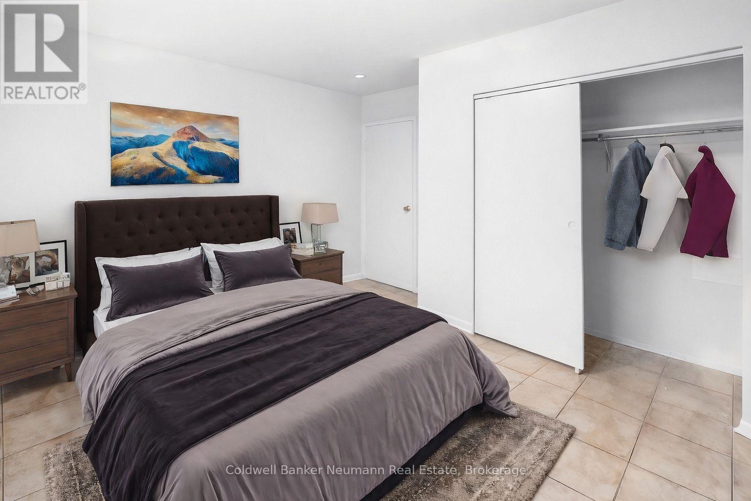 A bedroom with a large bed and a painting on the wall.