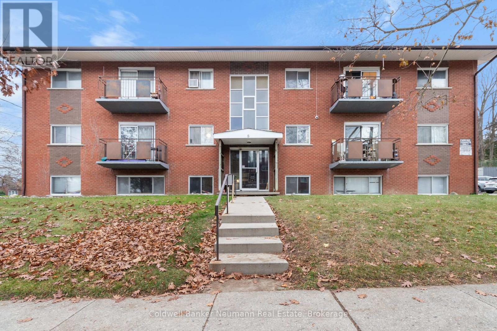 A red brick apartment building with a white door and steps leading up to it.