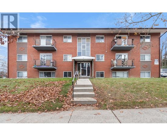 A red brick apartment building with a white door and steps leading up to it.
