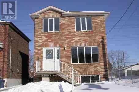 A brick house with a white door and windows is surrounded by snow.