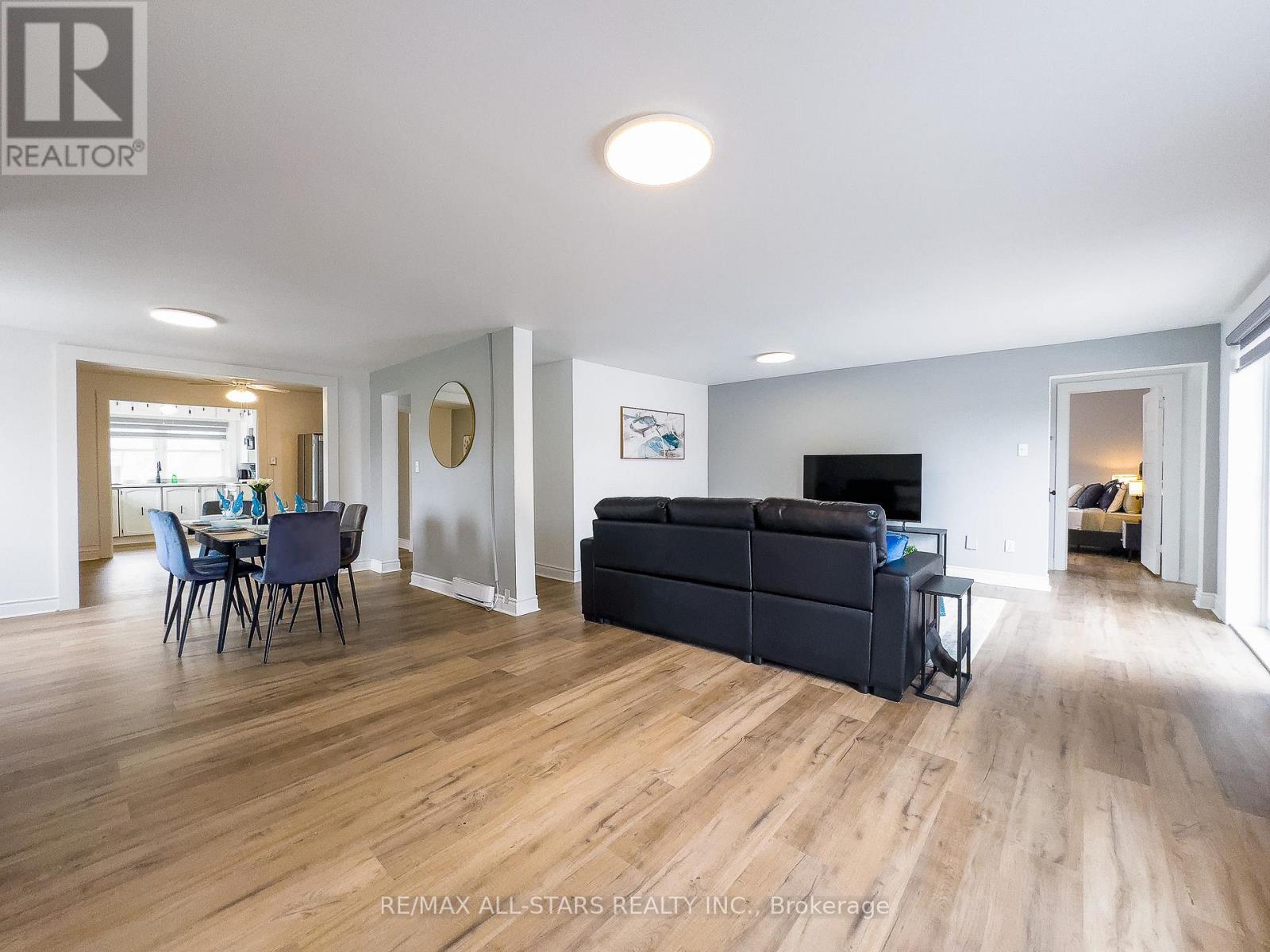 A spacious living room with a black couch and wooden flooring.
