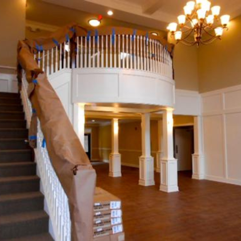 A staircase with a brown carpeted runner and a chandelier hanging from the ceiling.