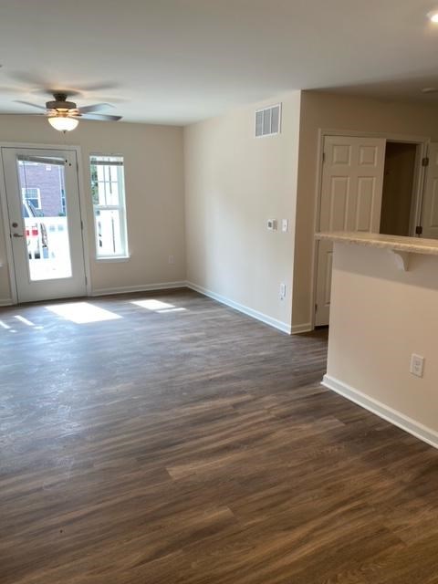 A room with a ceiling fan and wood flooring.
