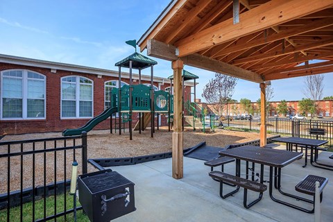 A playground with a green slide and a wooden roofed pavilion.