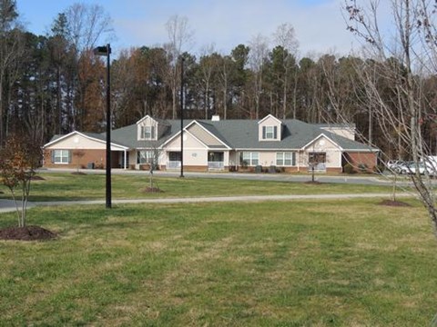 A large house with a green roof is surrounded by trees.