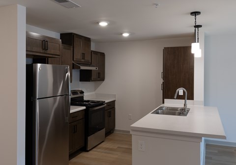 A modern kitchen with a stainless steel refrigerator and a white countertop.