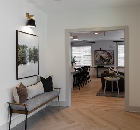A living room with a grey couch and a painting on the wall.