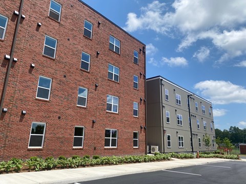 A red brick building with a parking lot in front.