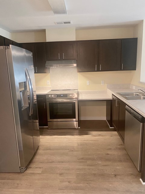 A modern kitchen with a stainless steel refrigerator and oven.