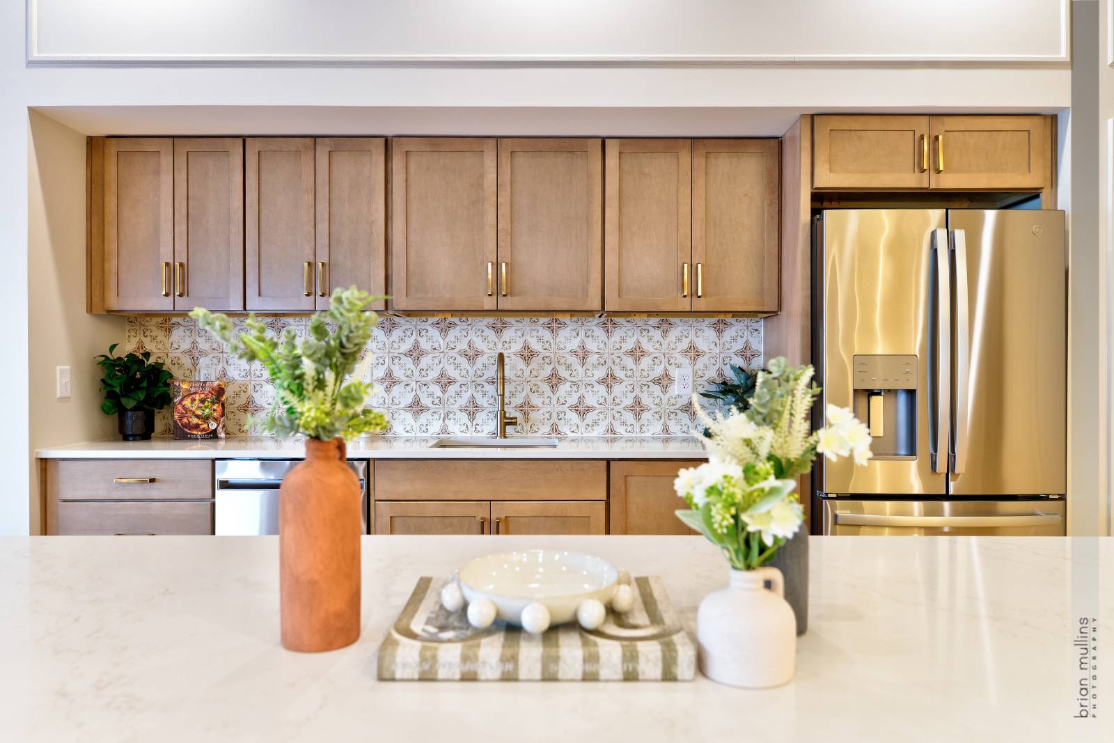A kitchen with a marble counter top and a gold refrigerator.