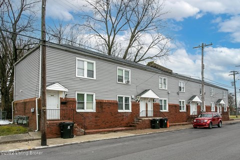 A row of houses with a red car parked in front of the first house.