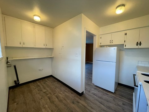 A kitchen with white cabinets and a white fridge.