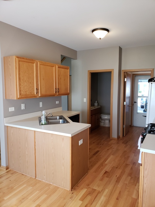 A kitchen with wooden cabinets and a white counter.