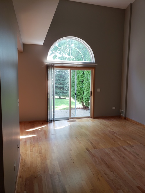 A room with wooden floors and a large arched window.