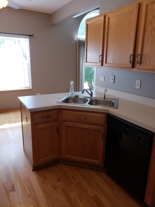 A kitchen with wooden cabinets and a black dishwasher.
