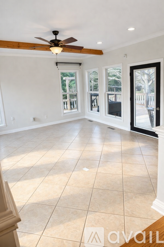 A spacious room with a ceiling fan and tiled flooring.