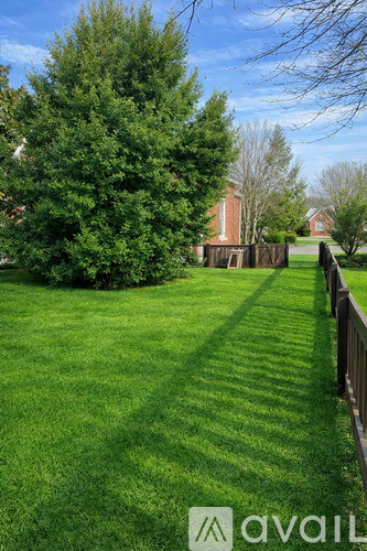 A grassy yard with a fence and a house in the background.