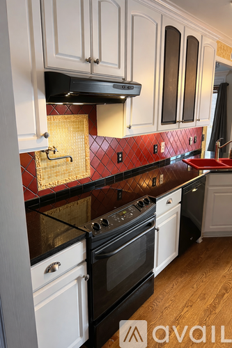 A kitchen with a black stove top oven and a white oven.