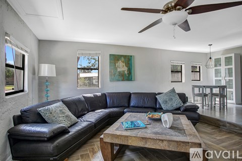 A living room with a large black leather sofa and a wooden coffee table.