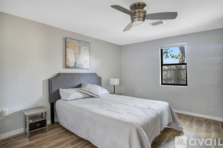 A bedroom with a bed, nightstand, and a ceiling fan.