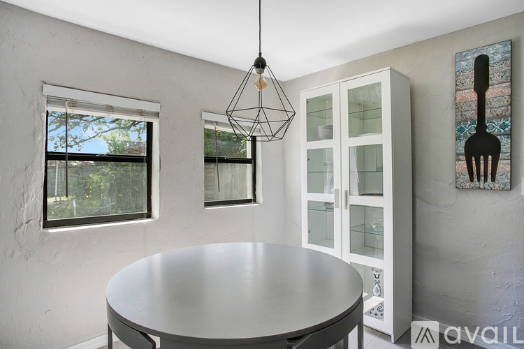 A modern dining room with a round table and a hanging light fixture.