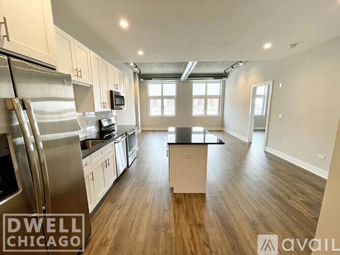 A spacious kitchen with stainless steel appliances and wooden flooring.