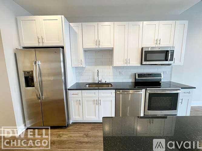 A kitchen with white cabinets and a stainless steel refrigerator.
