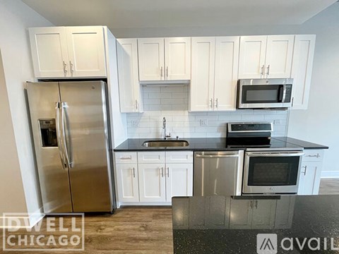A kitchen with white cabinets and a stainless steel refrigerator.