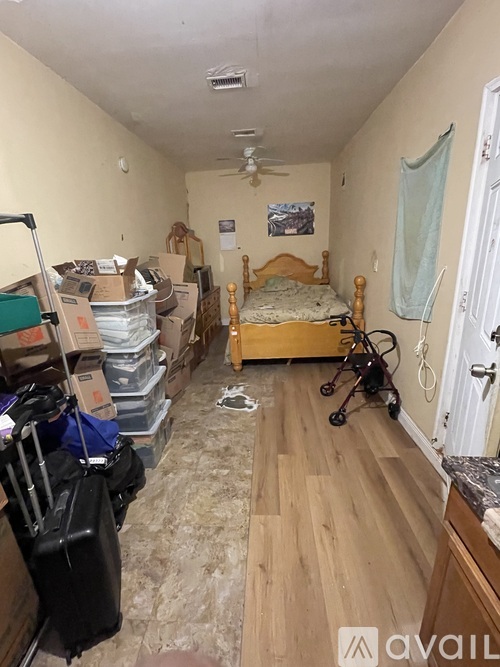 A room with a bed, a fan, and a stroller in it.