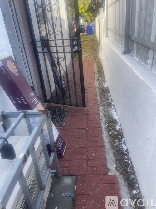 A white wall with a black gate and a red brick path.