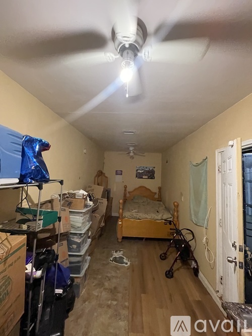 A room with a bed, a fan, and a stroller.