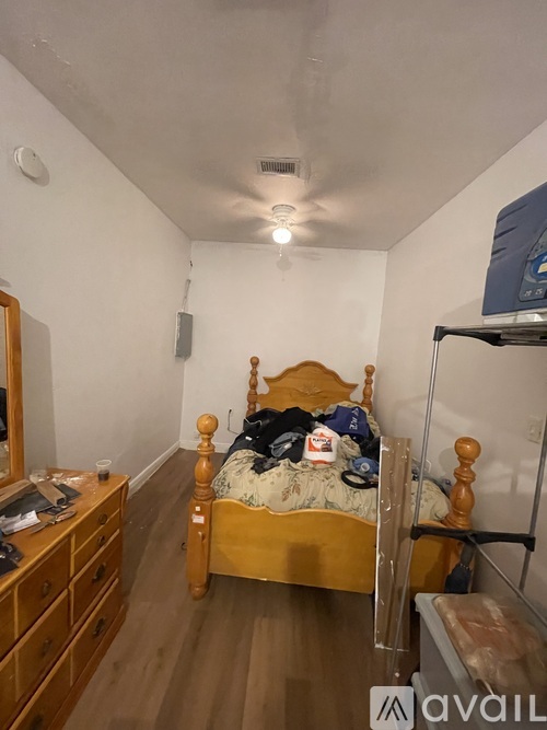 A bedroom with a bed, dresser, and shelves.