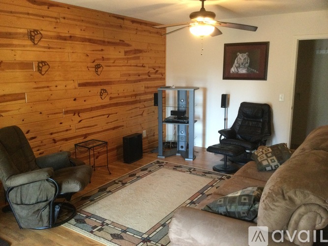 A living room with a wooden wall and a black leather chair.