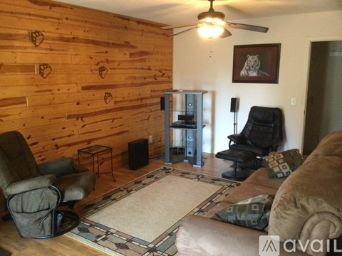 A living room with a wooden wall and a black leather chair.